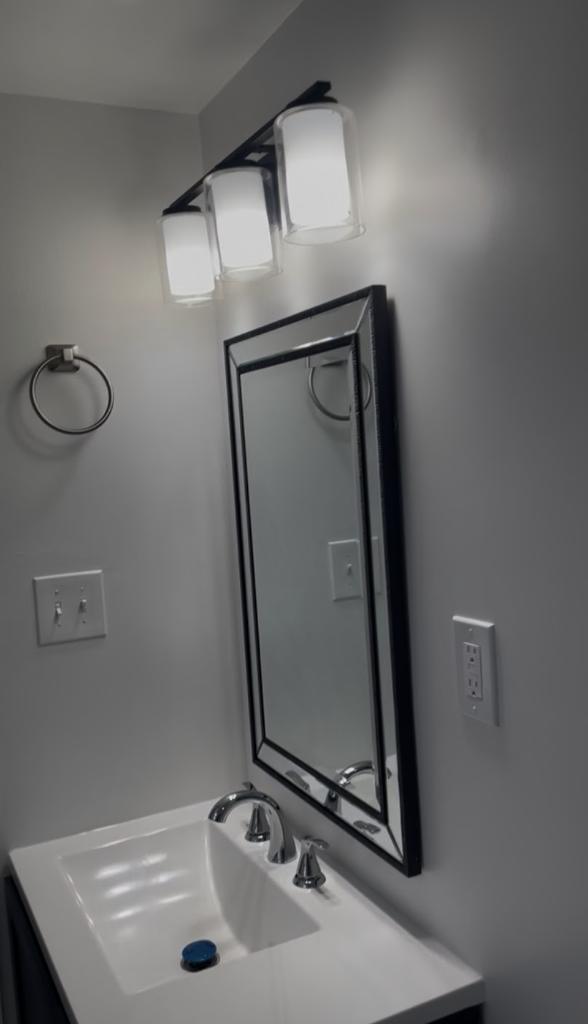 Bathroom vanity with framed mirror and light fixture