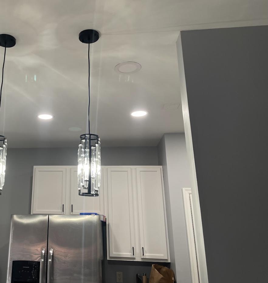 Kitchen with white cabinets, recessed lights and glass pendants