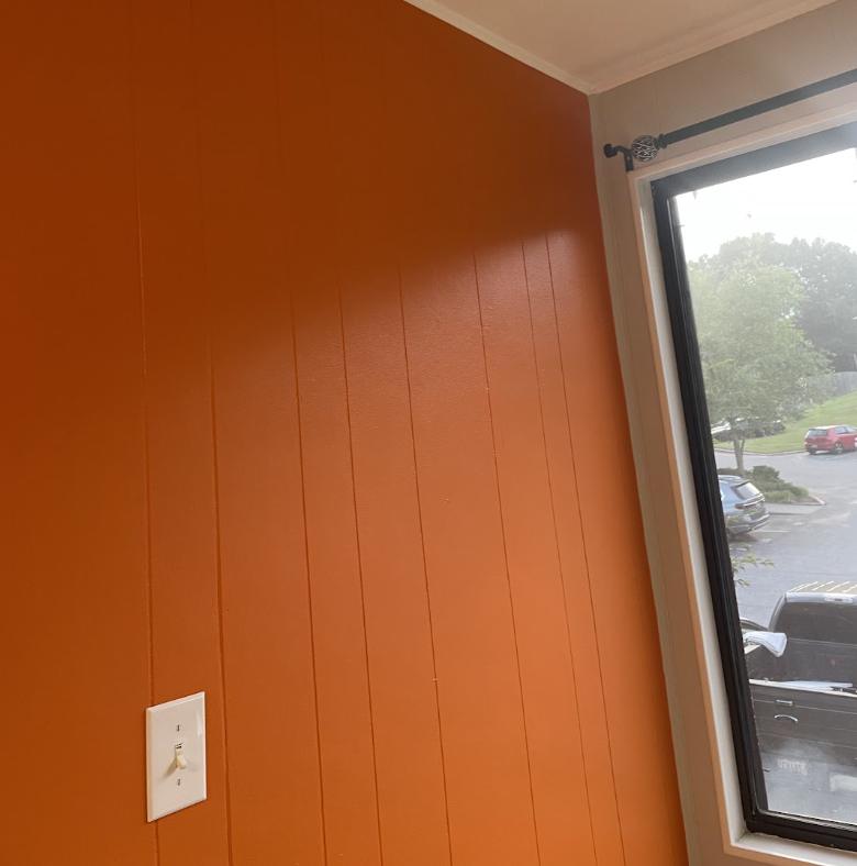 Orange painted wood panelling with white window trim